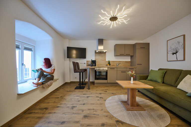Sofa mit kleinem Tisch, Sessel und glänzendem Kachel-Kamin in moderner Luxussuite